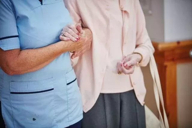 Carer holding hands with elderly resident